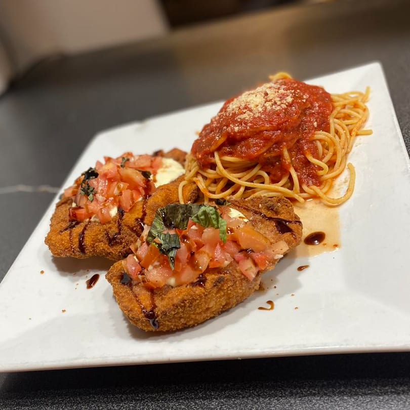 Chicken cutlets topped with bruschetta and balsamic glaze, served with spaghetti and marinara sauce.