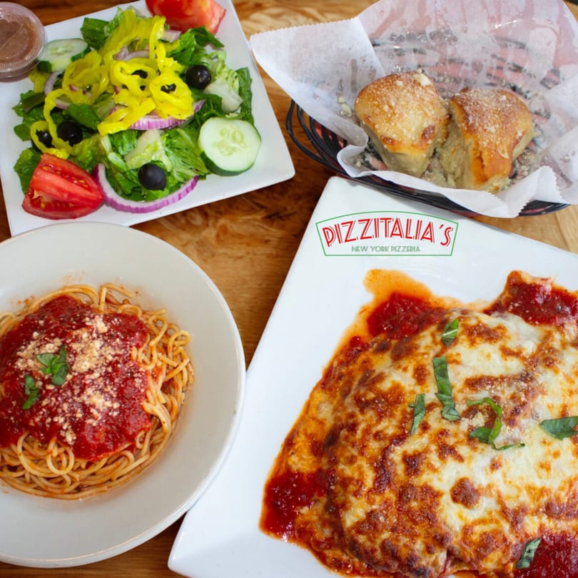 A full meal from Pizzitalia's, including spaghetti, chicken parmesan, salad, and garlic knots.