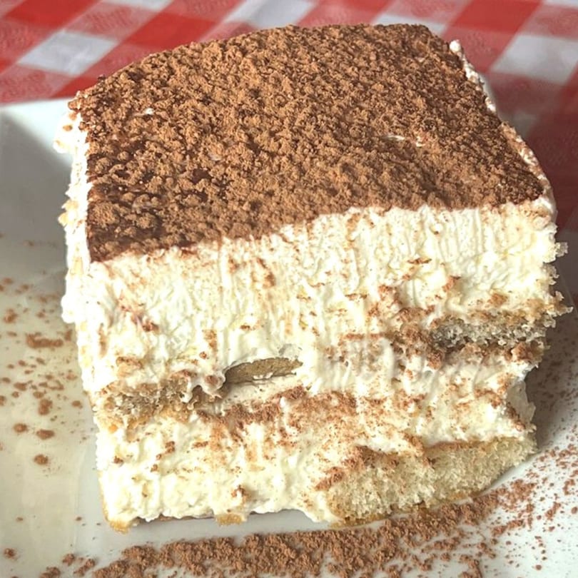 A generous slice of Pizzitalia's tiramisu, layered with cream and dusted with cocoa powder.