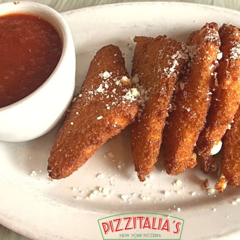 Golden-brown mozzarella sticks, sprinkled with cheese, served with a side of red marinara sauce.